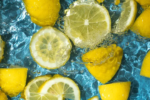 Yarım limon ve taze limon dilimlerinden oluşan sulu bir arkaplan.