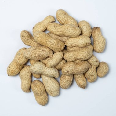 Kabuklu kabuklu soyulmamış fıstık yığını beyaz arka planda.