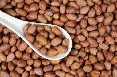 Kahverengi kabuklu çiğ fıstık çekirdekleri yakın plan kaşıkta.