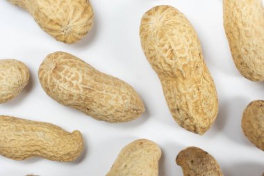 Beyaz arka planda soyulmamış bir sürü fıstık.