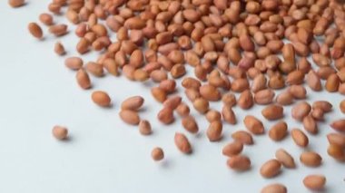 Beyaz arka planda, yavaş çekimde kurumuş fıstıklı çekirdeklerin dağılması..