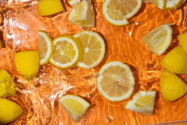 Suda taze limon dilimleri, biraz su, taze turuncu arka plan, üst manzara..