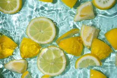 Turkuaz narenciye arkaplanı yüzen sarı limon parçalarıyla tazeleniyor.