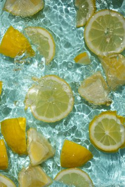 Turkuaz narenciye arkaplanı yüzen sarı limon parçalarıyla tazeleniyor.