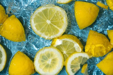 Yarım limon ve taze limon dilimlerinden oluşan sulu bir arkaplan.