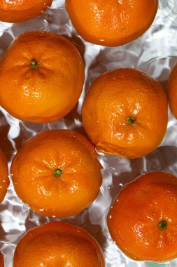 Temiz su manzarasına serpilmiş taze mandalinalar..