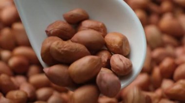 Kahverengi kabuklu çiğ fıstık çekirdekleri yakın plan kaşıkta.