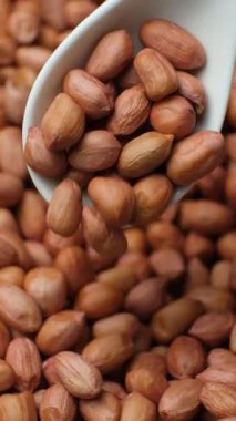 Kahverengi kabuklu çiğ fıstık çekirdekleri, dikey ağır çekimde..