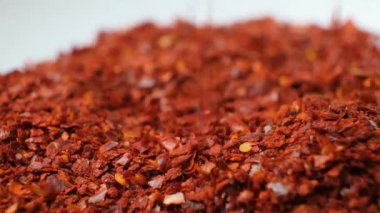 Ezilmiş kırmızı kırmızı biber doğal baharat beyaz arka planda, yavaş çekim.