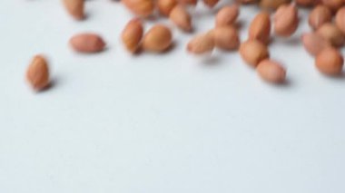 Beyaz arka planda, yavaş çekimde kurumuş fıstıklı çekirdeklerin dağılması..