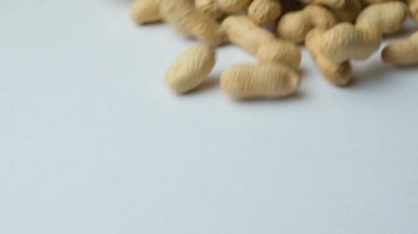 Kabuklu kabuklu soyulmamış fıstıkların beyaz arka planda yavaş çekimde dağılması..