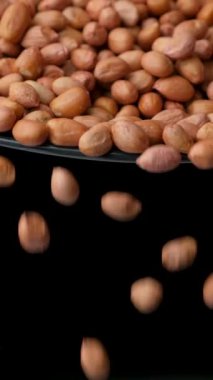 Çiğ, kurutulmuş fıstık çekirdekleri dökülür, yakın çekim, dikey yavaş çekim.