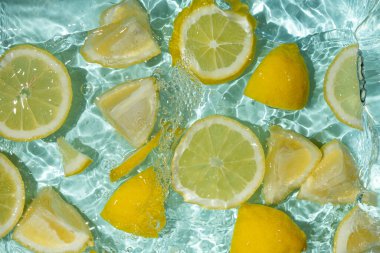 Turkuaz narenciye arkaplanı yüzen sarı limon parçalarıyla tazeleniyor.