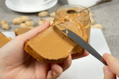 Ekmeğe fıstık ezmesi sürme süreci, eller yakın çekim.