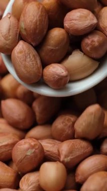 Kahverengi kabuklu çiğ fıstık çekirdekleri yakın plan kaşıkta.