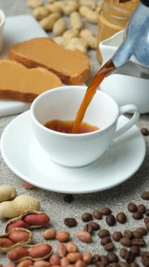 Kahve fincana dökülür. Kahveyle kahvaltı ve fıstık ezmeli tost. Dikey ağır çekim.