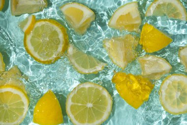 Turkuaz narenciye arkaplanı yüzen sarı limon parçalarıyla tazeleniyor.