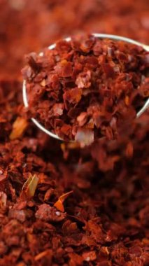 Ezilmiş kırmızı kırmızı biber, doğal baharatlı, dikey ağır çekimde..