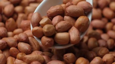 Kahverengi kabuklu çiğ fıstık çekirdekleri yakın plan kaşıkta.