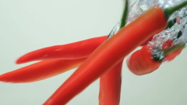 Sıcak kırmızı biberler yavaş çekimde suya daldırılıyor.
