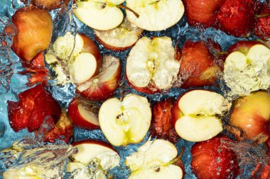 Sulu yaz ya da sonbahar arkaplanı. Kırmızı elma yarımları ve suda