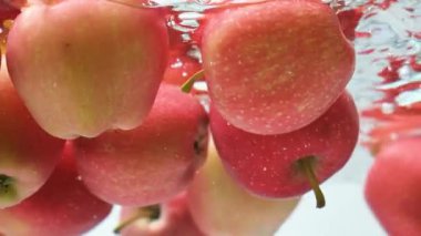 Yüzen kırmızı elmaların estetik sualtı görüntüsü.