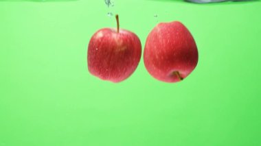 Düşen kırmızı elmaların sualtı görüntüsü. Sudaki Meyveler Yavaş Harekette
