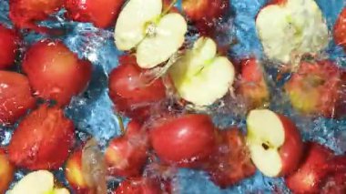 Kırmızı elmaların yarıları suya düşüyor, bir damla su, yavaş çekim.