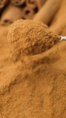 Yerdeki tarçın kaşık makrodan akıyor. Ağır çekim dikey çekim