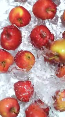 Yavaş hareket eden elmalar suya düşüyor. Su sıçraması, üst görünüm dikey.