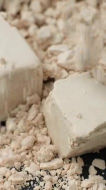 Sıkıştırılmış taze maya dikey ağır çekimde dökülüyor.