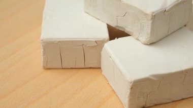 Sıkıştırılmış taze maya küpleri ahşap arka planda yakın plan.