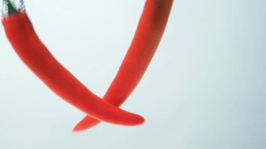 Baloncuklarla berrak suya dökülen baharatlı biberler.