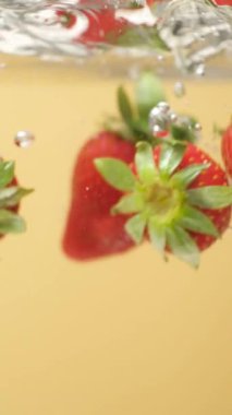 Olgun Çilek, berrak suya batıyor. Yavaş Hareket Hava Kabarcıklarıyla Sıçrama