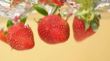 Olgun Çilek, berrak suya batıyor. Yavaş Hareket Hava Kabarcıklarıyla Sıçrama