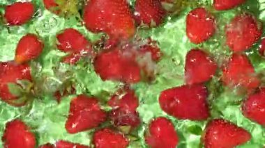 Suda taze çilek parçaları, biraz su, üst manzara, yavaş çekim.