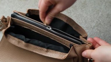 Kadınların deri çantasının iç cebindeki fermuarı açıp kapatıyorum.