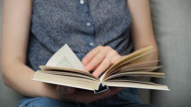 Kadın kitap okuyor, sayfaları çeviriyor.