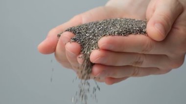 Eller Chia tohumlarını yavaş çekimde döker. Organik süper gıda bileşeni