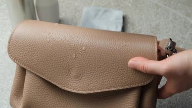 Deri bir el çantasının yüzeyini temizliyorum. Püskürtme uygulaması ve bez ile silme, yavaş çekim.