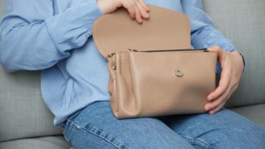 Küçük deri kadın çantasını açıp kapayan bir kadın.