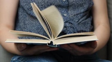 Ellerinde bir kitap, sayfaları çeviriyor, ağır çekimde. Bilgelik ve bilgi kavramı