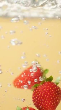 Olgun Çilek, berrak suya batıyor. Yavaş Hareket Hava Kabarcıklarıyla Sıçrama