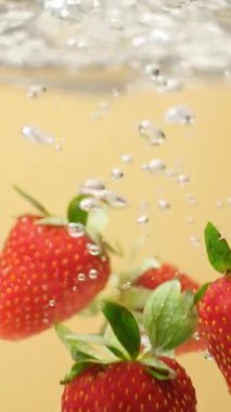 Olgun Çilek, berrak suya batıyor. Yavaş Hareket Hava Kabarcıklarıyla Sıçrama