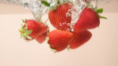 Suyun içinde canlı bir çilek. Dramatik Su Sıçratma ve Yüzen Baloncuklar