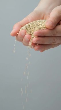 Elleri pişmemiş çiğ beyaz kinoa, dikey ağır çekimde.