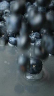 Taze yaban mersinleri suya dökülüyor. Su makro yavaş çekim dikey çekim.