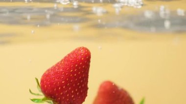 Olgun Çilek, berrak suya batıyor. Yavaş Hareket Hava Kabarcıklarıyla Sıçrama