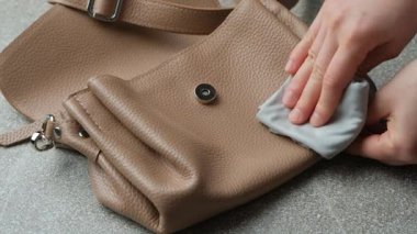 Deri bir çantayı bezle silmek, aksesuarlarla ilgilenmek. Yavaş çekim.