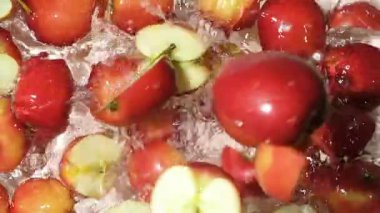 Kırmızı elmaların yarıları suya düşüyor, bir damla su, yavaş çekim.